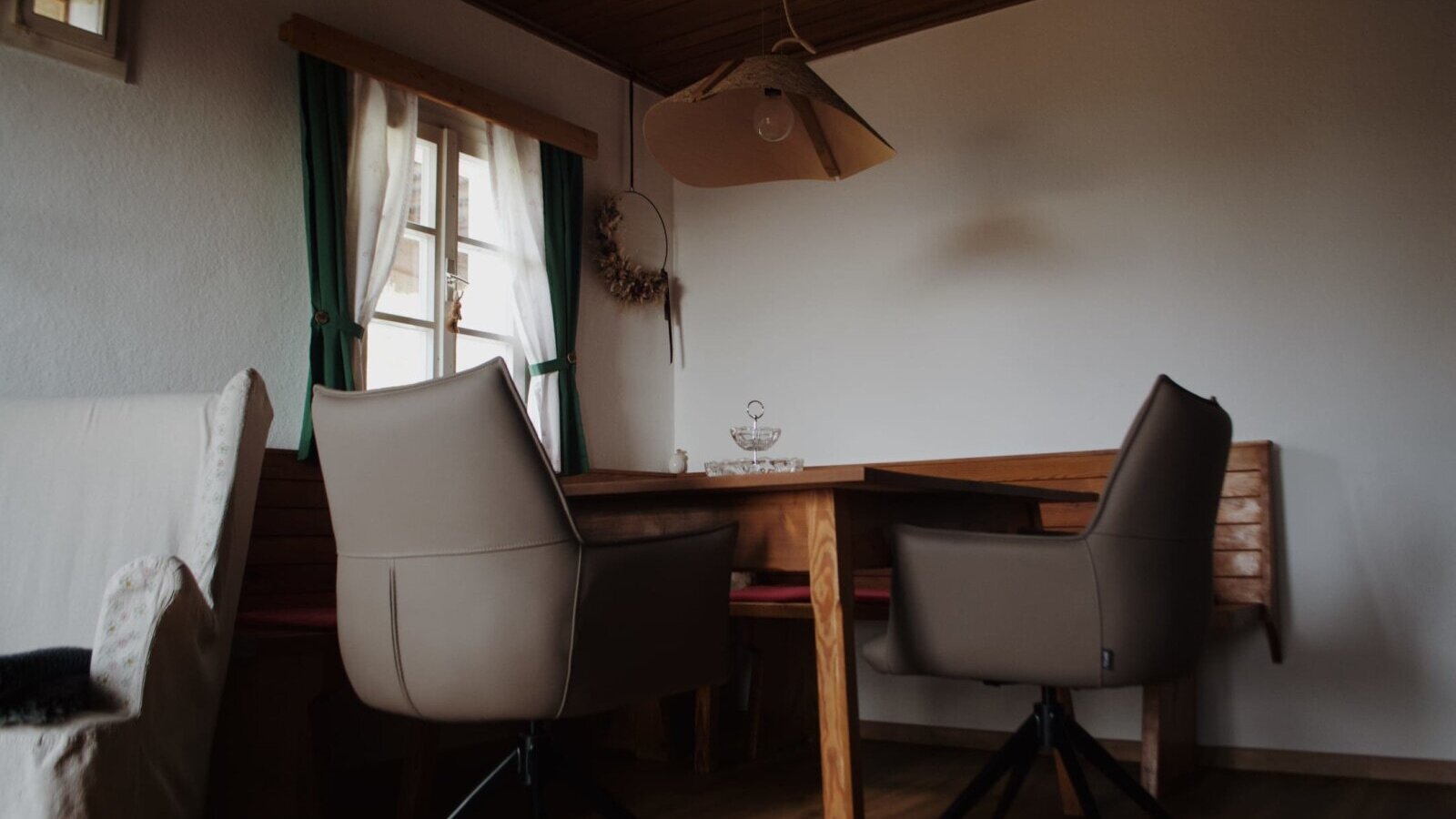 Dining are with a wooden table, chairs, corner bench, and window.