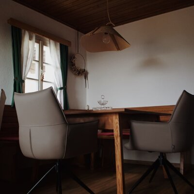Dining are with a wooden table, chairs, corner bench, and window.