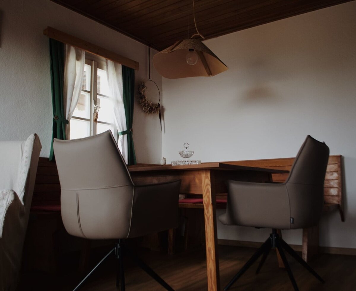 Dining are with a wooden table, chairs, corner bench, and window.