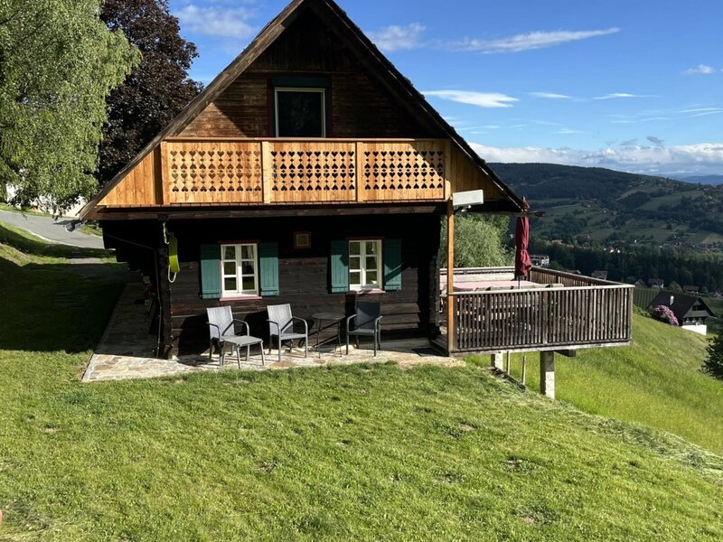 Exterior view of the cottage with a balcony, terrace, and mountain views.