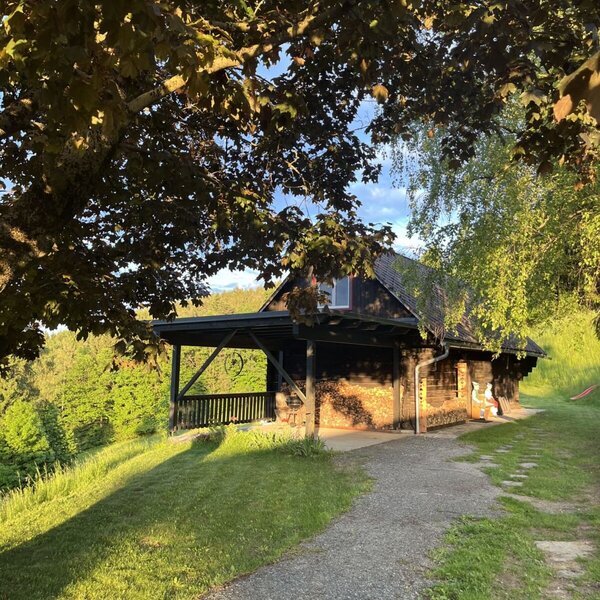 Exterior view of the farmhouse with a wooden facade, covered porch, and a gravel path.
