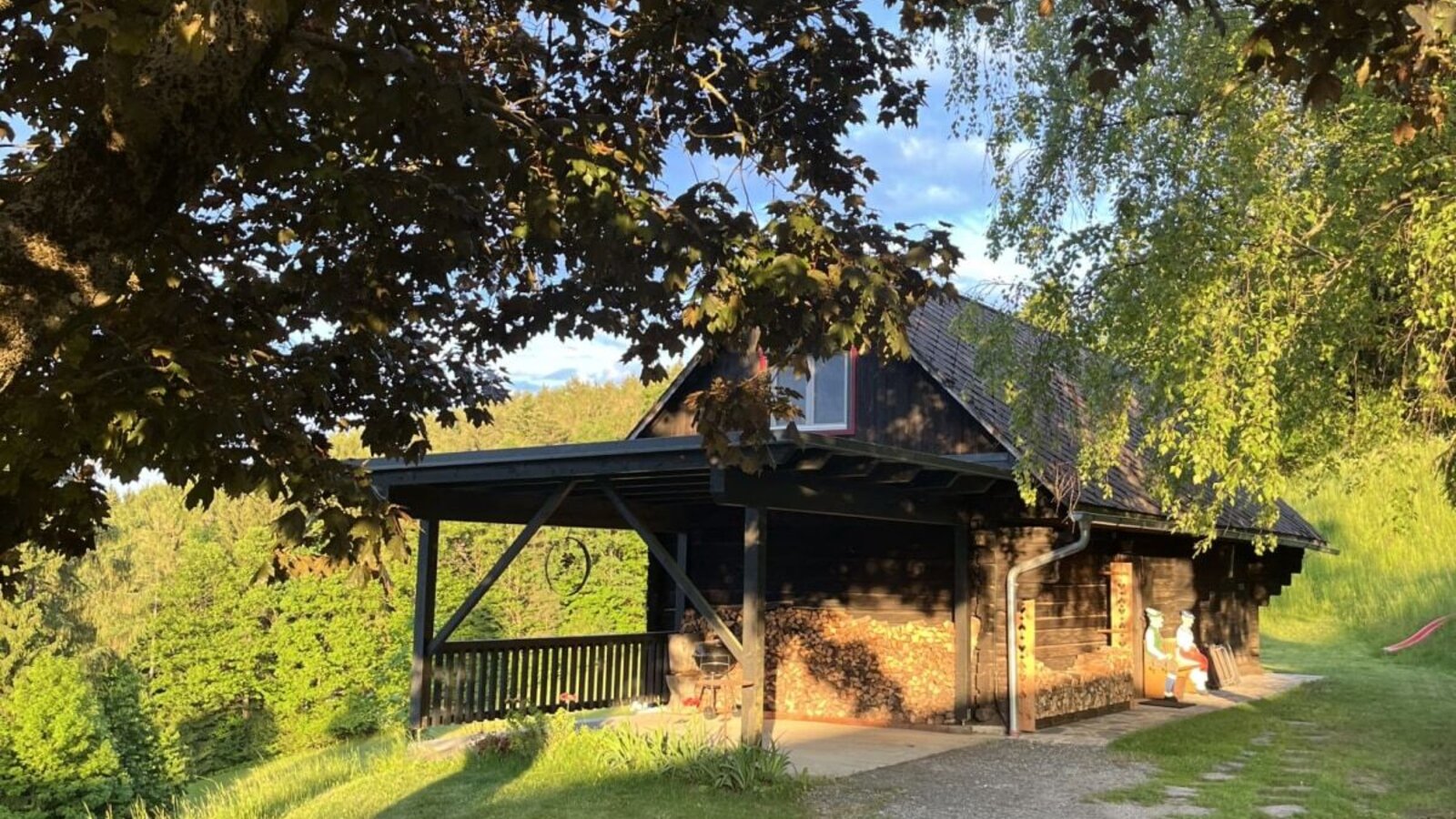Exterior view of the farmhouse with a wooden facade, covered porch, and a gravel path.