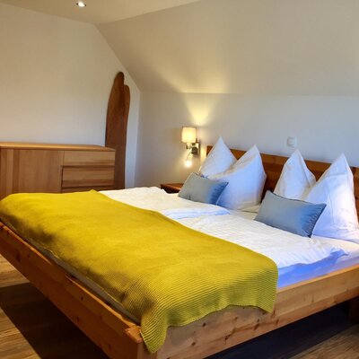 Bedroom in the farmhouse with a pine wood bed and wooden dresser.