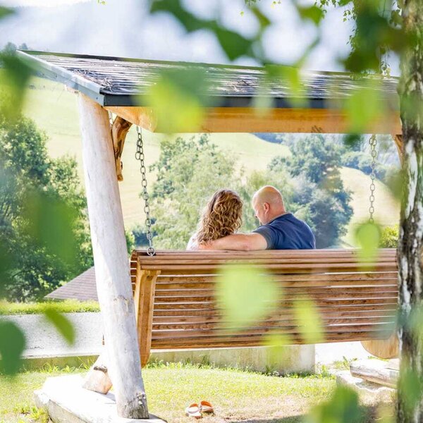 An inviting wooden swing in the farmhouse's garden, offering scenic views of the rolling green hills.