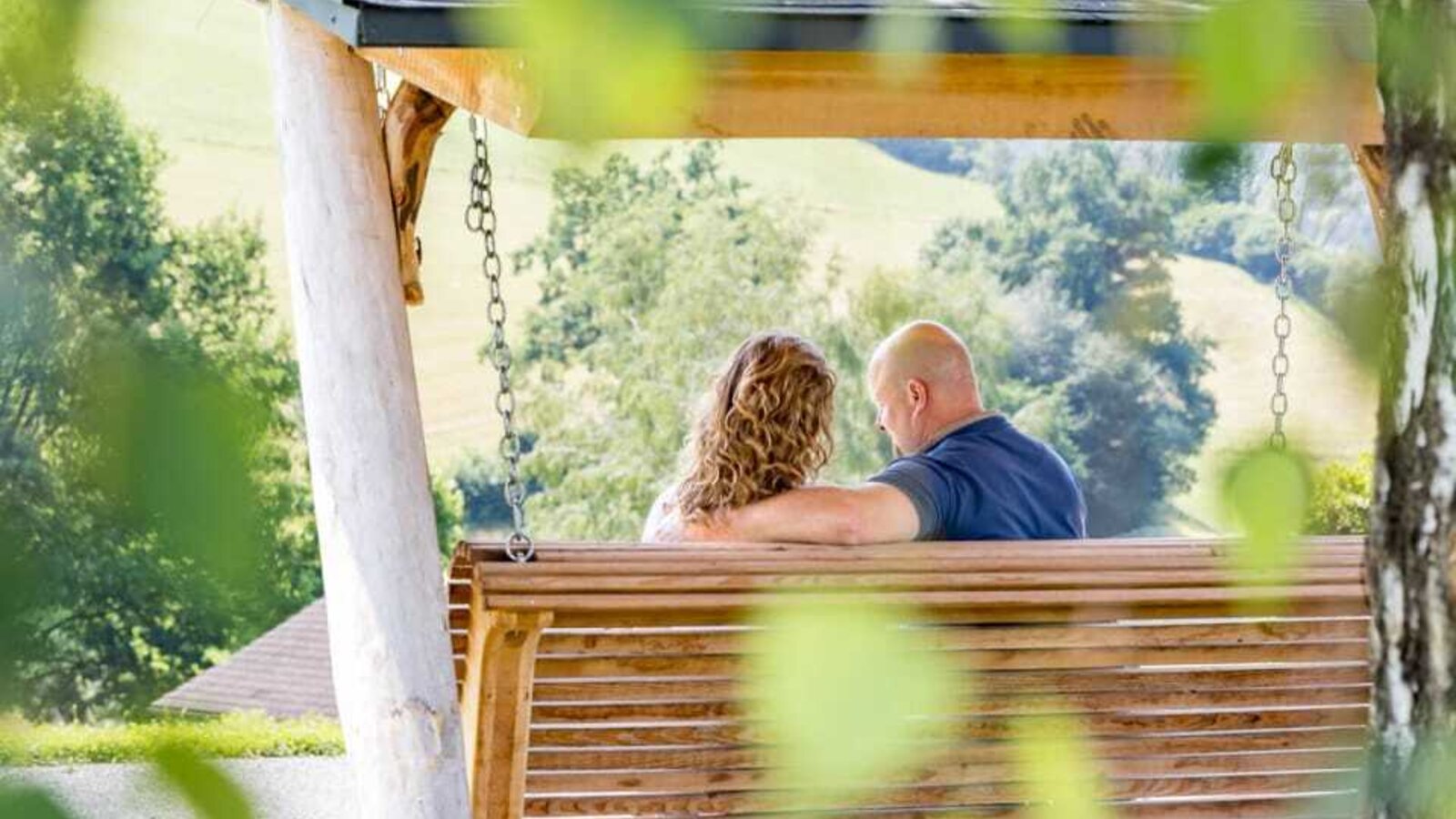 An inviting wooden swing in the farmhouse's garden, offering scenic views of the rolling green hills.