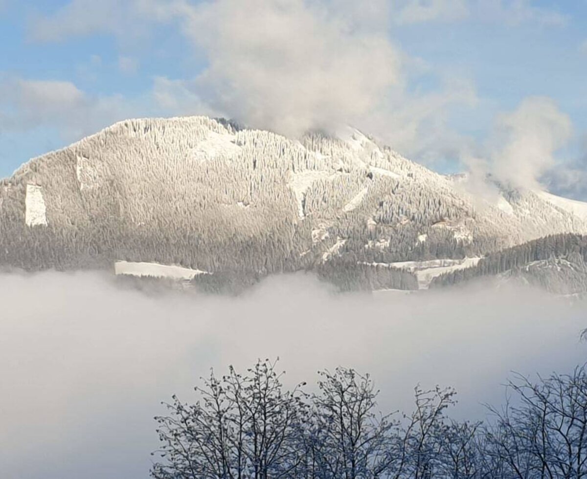 View of snow-covered mountains, with their lower slopes enveloped in fog, forming the natural landscape around the Farm House.