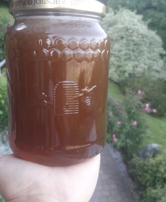 Locally sourced blossom honey in a jar with honeycomb and beehive details, available at the Farm House.