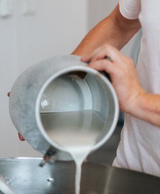 Milk being poured from a pitcher, highlighting the farmhouse's famous yoghurt. (yoghurt).
