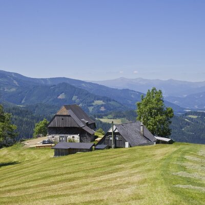 The little cottage, a group of traditional buildings, is situated on a green hillside with magnificent mountain views.