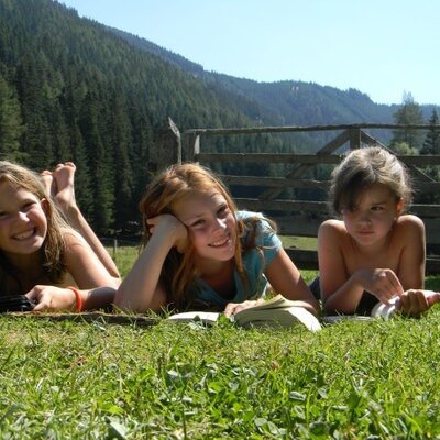 Children enjoying the outdoor grass area at the farmhouse, with a mountain view.