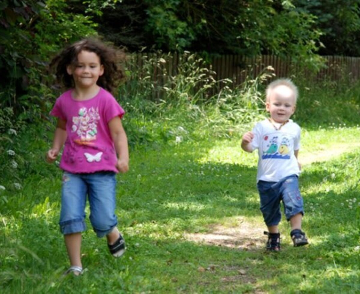 Children running on a grassy path in the outdoor area of the farmhouse.