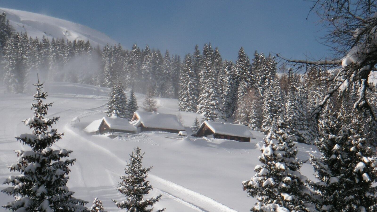 The farmhouse in a snow-covered winter landscape, featuring traditional wooden buildings and pine trees.