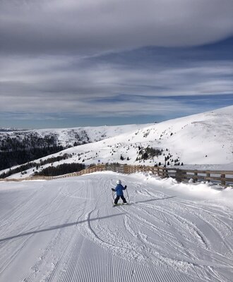 A skier on a groomed mountain slope surrounded by snow-covered landscapes, reflecting the winter activities available in the vicinity of the farmhouse.
