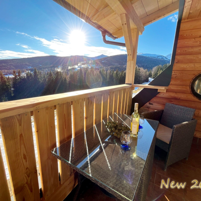 Sunny balcony of the Grosserhütte with a wide view of the forested mountain landscape.