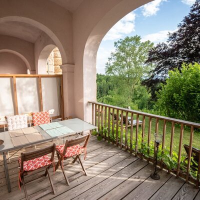 An inviting, covered terrace featuring a cozy dining area and scenic views of the lush green surroundings.
