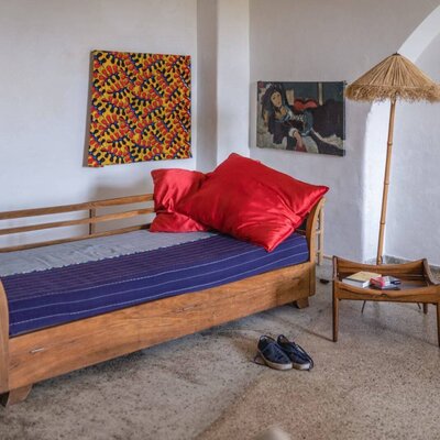 A cozy daybed with vibrant red pillows and colorful wall art in this rustic farmhouse.