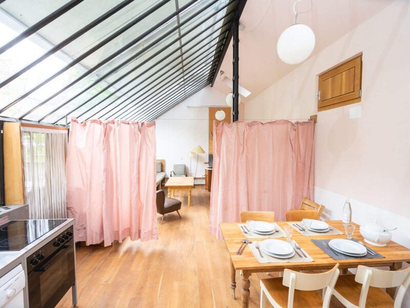 The apartment's inviting dining and living area, featuring a self-catering kitchen setup and abundant natural light under a large glass roof.