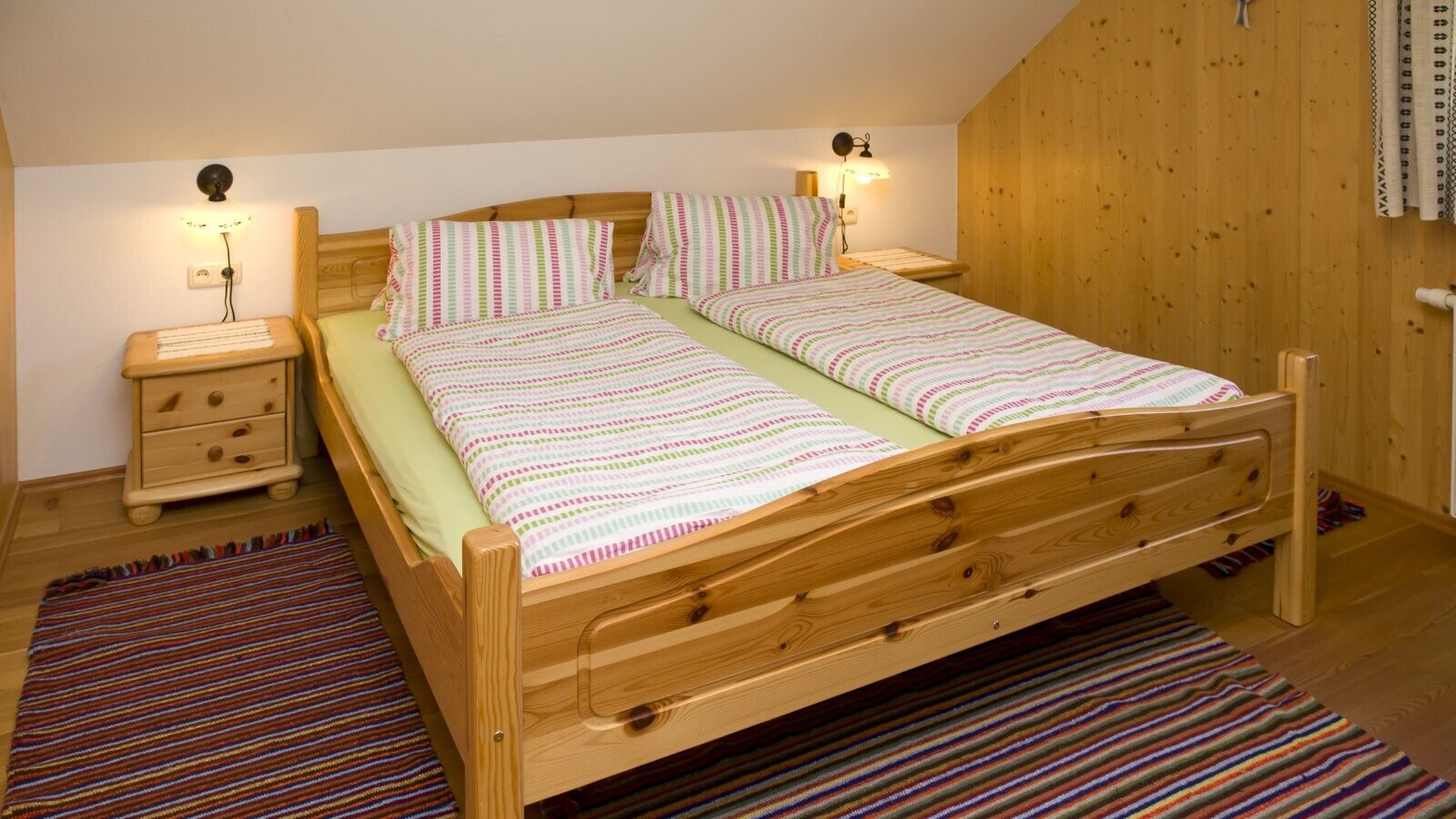 Double bedroom in the farmhouse with a wooden bed frame, two bedside tables, and wall-mounted reading lamps.