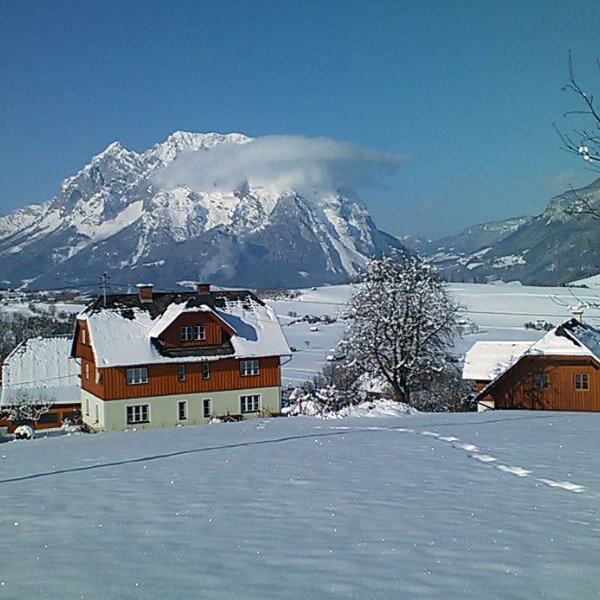 The farm house and surrounding landscape covered in snow, with views of the Enn valley and mountains in the background. The farm house and surrounding landscape covered in snow, with views of the Enn valley and mountains in the background.