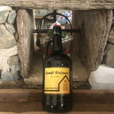 A bottle of Sankt Stefaner Hausi-Bier, a local specialty, presented on a wooden surface in the farmhouse.