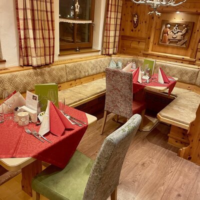 Dining area in the farmhouse with wood paneling, upholstered bench seating, and set tables.