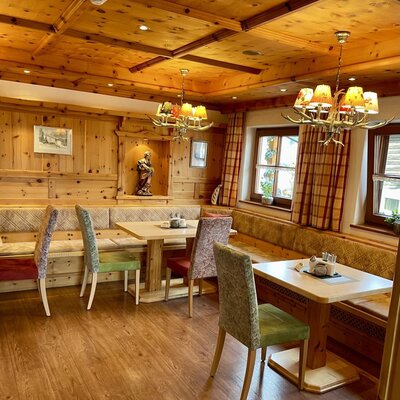 Dining area of the farmhouse with wooden paneling, upholstered corner benches, and tables.