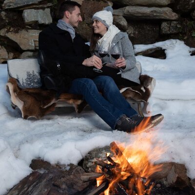 The Farm House offers an outdoor seating area with a bonfire, surrounded by snow.