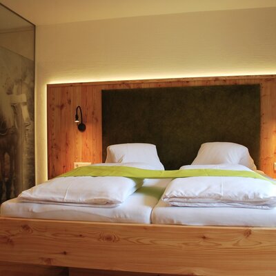 Spacious bedroom in the farmhouse with a double bed, wooden paneling, and alpine-style furnishings.