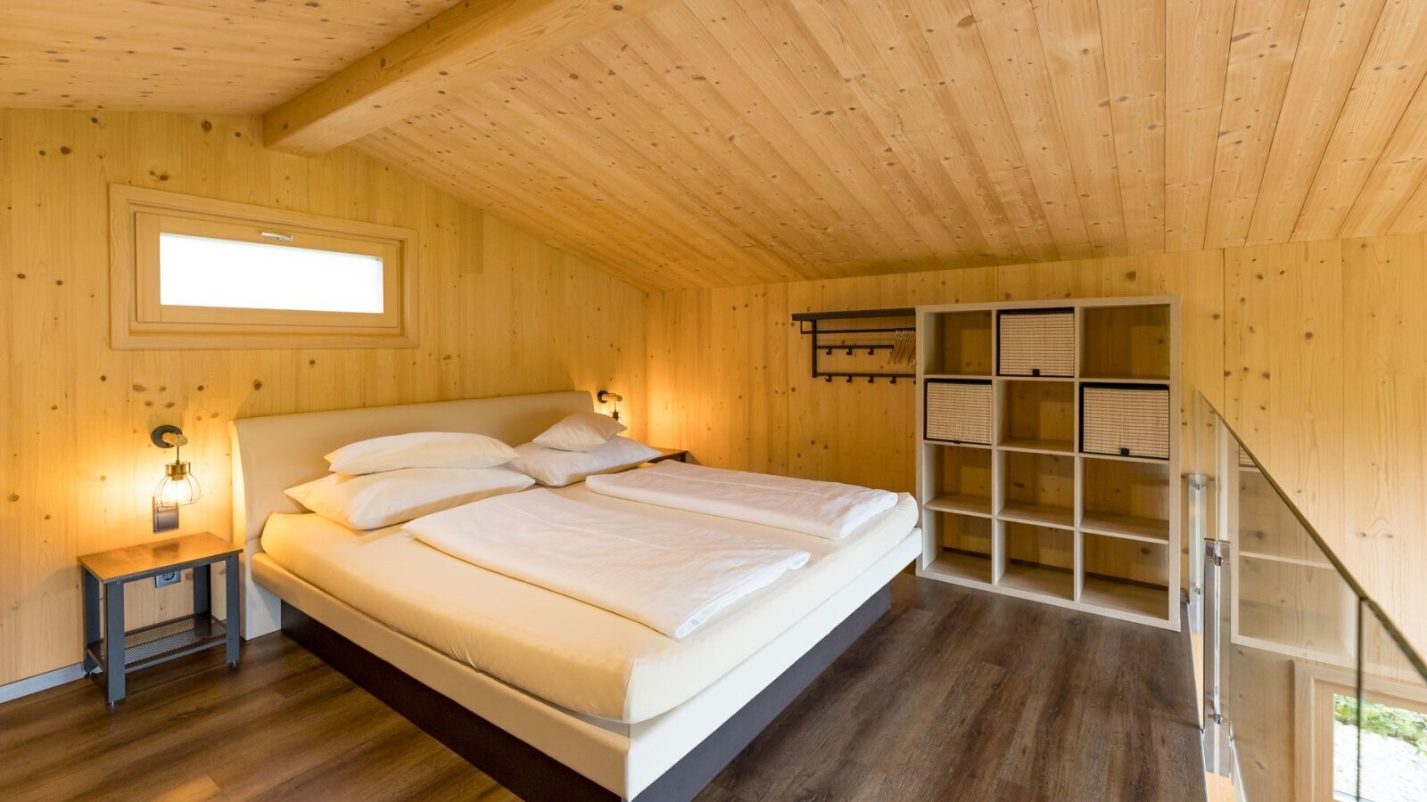 Bedroom in the chalet with box spring bed or waterbed, wood paneling and storage shelf. copyright: ELISABETH FRÖHLICH photography
