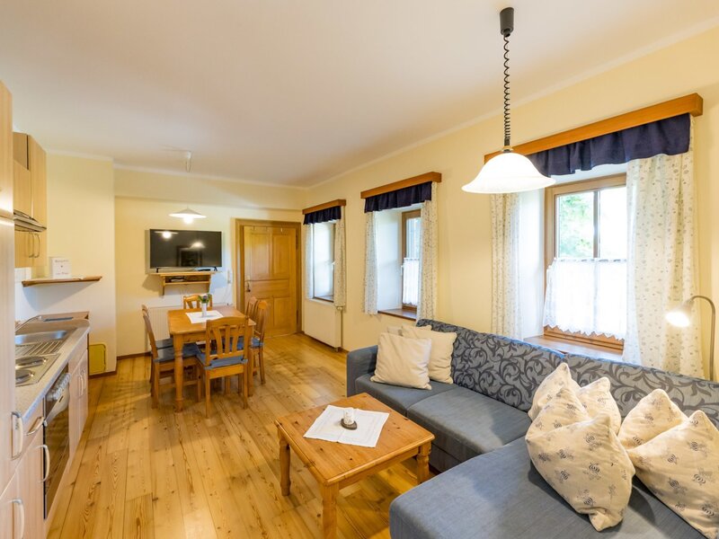 Cozy kitchen-living area in the farmhouse featuring an inviting sofa, a rustic wooden dining set, and a practical kitchenette.
