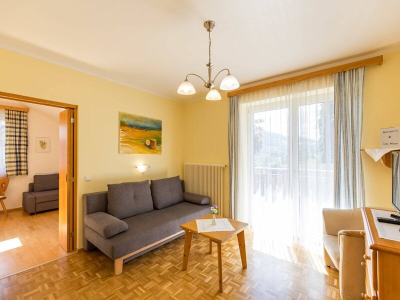 A bright family room in the farmhouse featuring a cozy sofa area, wooden flooring, and direct access to the balcony.