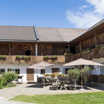 The farmhouse's inviting courtyard with cozy seating areas under shady sun umbrellas.