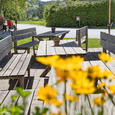 The farmhouse's inviting terrace features rustic wooden benches and shading parasols.