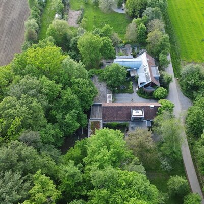 Aerial view of the farmhouse, surrounded by trees, fields, and an access road.