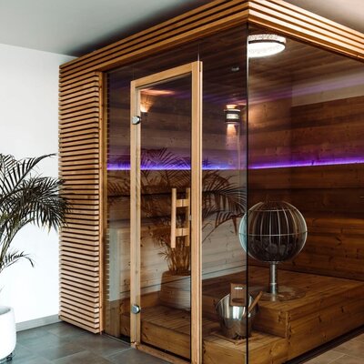The farmhouse provides a sauna with a wooden slatted exterior, a glass door, and an internal spherical heater for guest use.