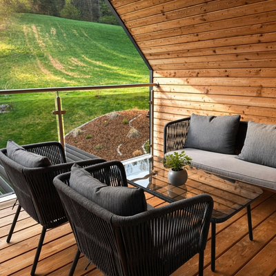 An inviting, wood-paneled balcony at the farmhouse featuring comfortable lounge seating and views of the green hillside.