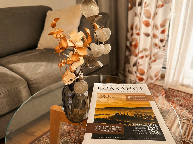 An elegant glass coffee table in the doubleroom, featuring stylish floral decor and information brochures in front of a cozy sofa.