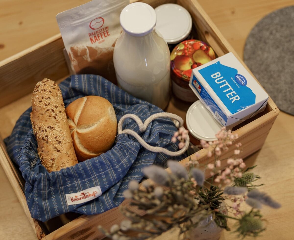 Farmhouse breakfast basket with bread, rolls, coffee, milk, butter, and jam.