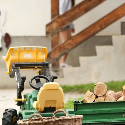 Toy tractor with a trailer full of logs for children at the farmhouse.