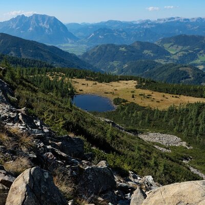 Scenic mountain view looking down on an idyllic alpine lake and the expansive landscape surrounding the farmhouse.