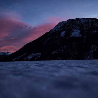 The farmhouse's scenic view of the snow-covered mountain range under a colorful dusk sky.