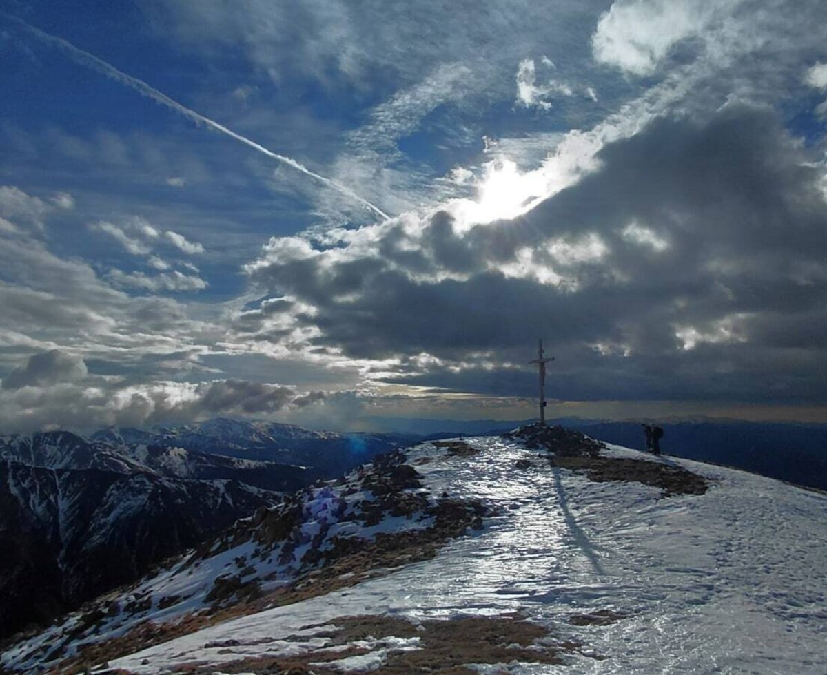 Mountain peak with summit cross Greim, 2474 and wide mountain panorama under a cloudy sky.