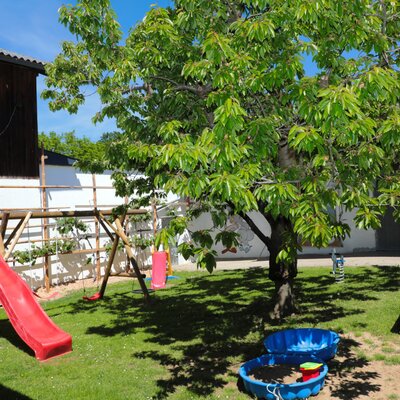 The farm house features an outdoor play area with a slide, swings, sandboxes, and a picnic table in the garden.