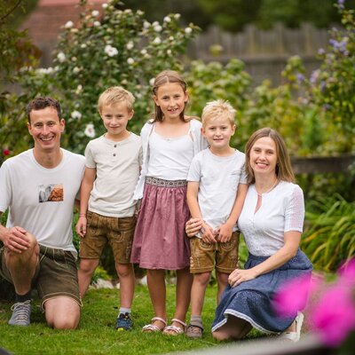 The farmhouse family with two adults and three children in the garden.