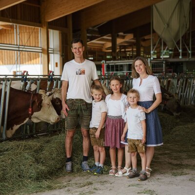 The Linharterhof farmhouse family with cows in the barn.