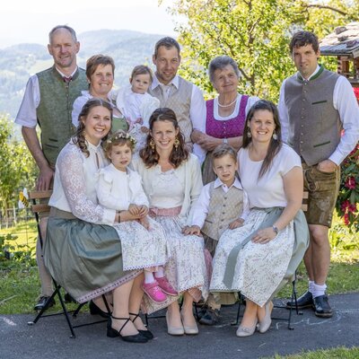 The welcoming host family of the farmhouse in traditional attire, set in the scenic garden.