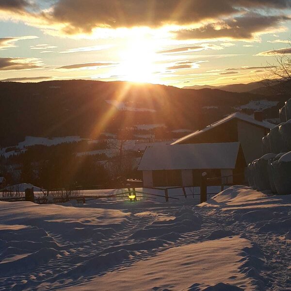 Sunset view over snow-covered fields and mountains from the farm house. Sunset view over snow-covered fields and mountains from the farm house.