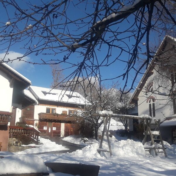 The Farm House exterior and grounds covered in snow, featuring balconies and a swing set.