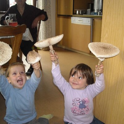 Children displaying large wild mushrooms in the Farm House kitchen.