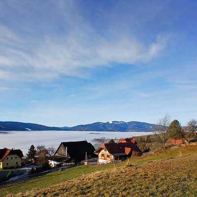 The surroundings of the farmhouse, featuring a village, church, fog in the valley, and mountains in the background.